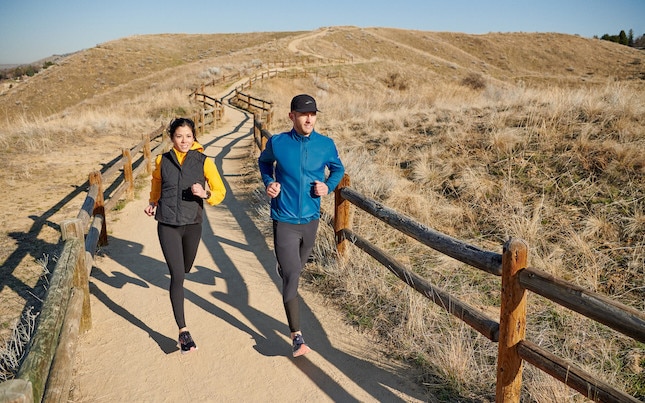 Two runners on a sandy path in the countryside.