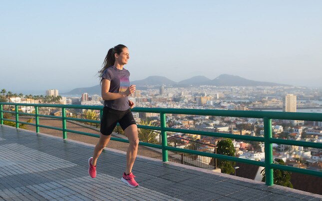 A solo runner on a path overlooking a city.