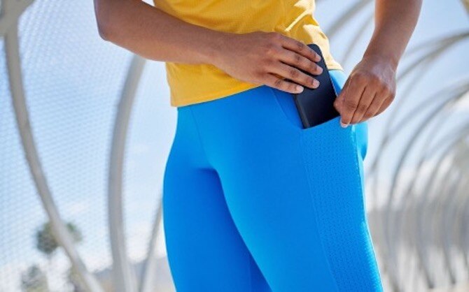 Femme mettant un téléphone dans la poche de son legging