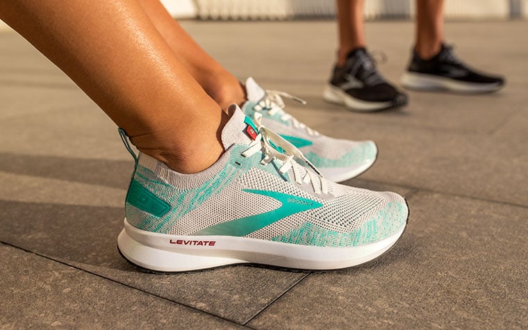 Les pieds d’un coureur avec les Levitate vertes et grises. Dans le fond, un autre coureur porte les Levitate noires.
