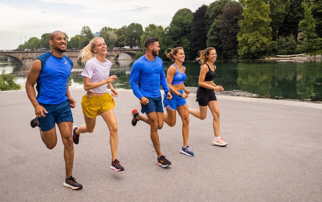 A diverse group of five runners during a workout with a river in the background.