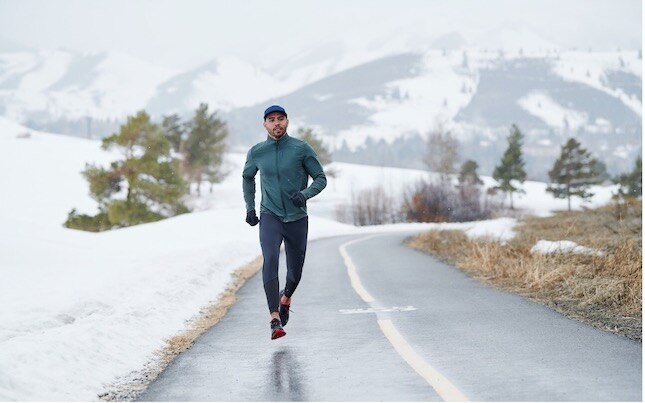 Un coureur sur une route enneigée en hiver.
