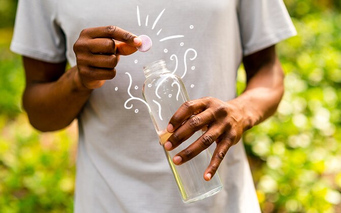 Quelqu’un qui dépose un comprimé Nuun dans une bouteille d’eau