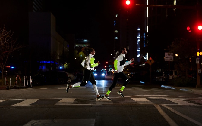 Side view of two runners crossing a street in the dark