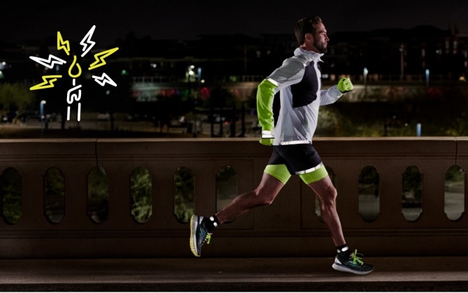 Seitenansicht eines Läufers, der nachts auf einer Straße läuft und eine reflektierende Ausrüstung trägt
