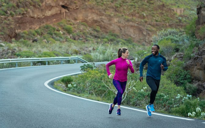 Two people running down a windy road