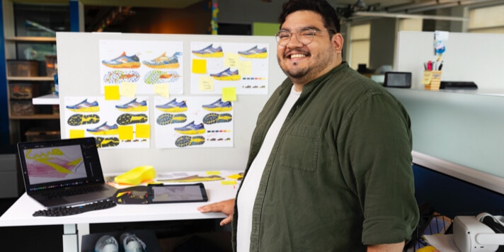 Homme debout devant un bureau avec des modèles de chaussures
