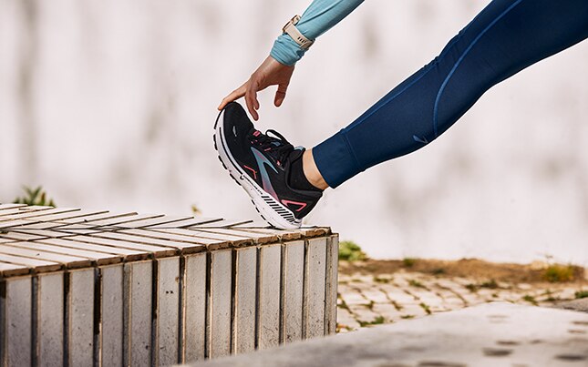 Close-up van de benen van twee hardlopers die Brooks Adrenaline GTS-schoenen met GuideRails-technologie dragen. 