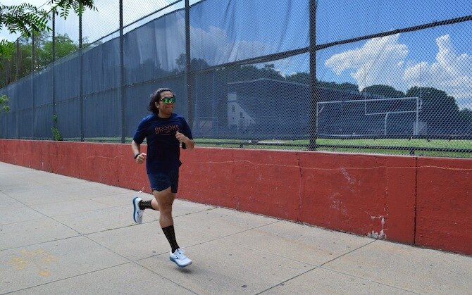 Runner running by a tennis court
