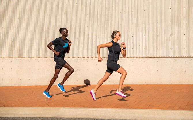 Two runners with a concrete wall behind them