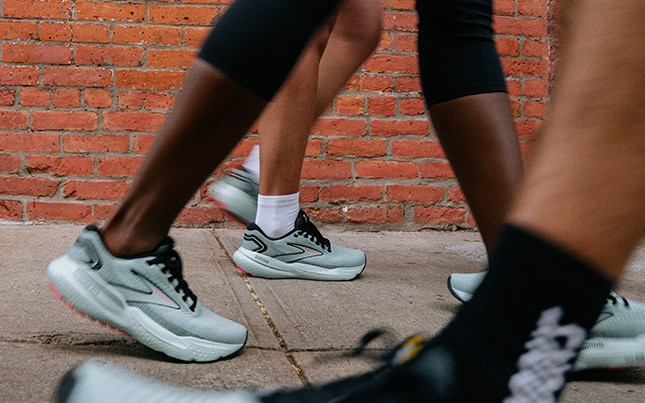 Nahaufnahme der Füße zweier Personen, die Brooks Glycerin 21 auf Asphalt tragen