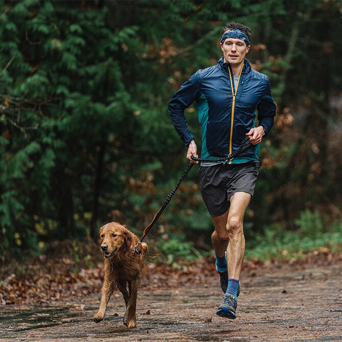 Man running down a trail with his dog