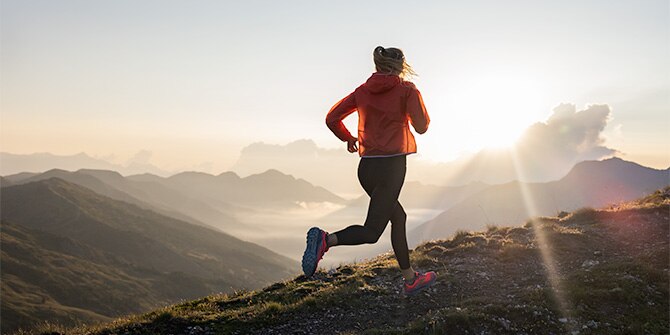 A runner on a trail at sunset