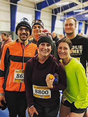 A group of five runners, all with bib numbers, pose together after a race.