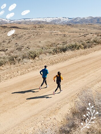 Runners on a sandy road with mountains afar