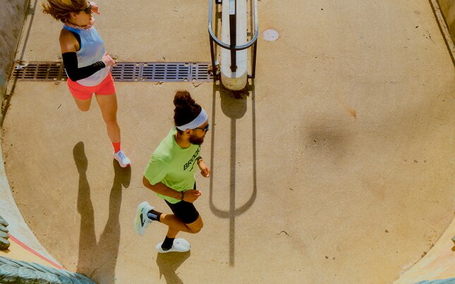 Two people running down a rocky trail.