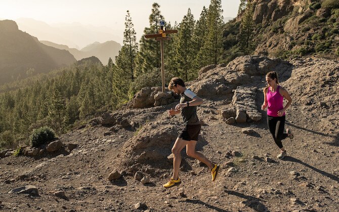 Two people running down a rocky trail.