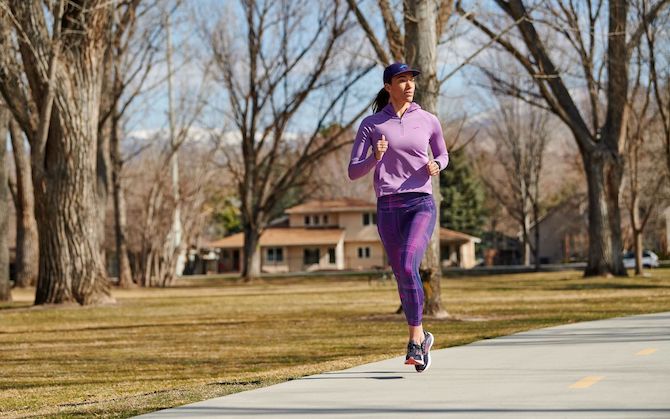 A runner jogs through a wooded residential neighborhood.