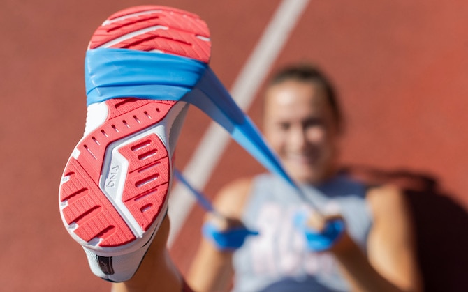 Runner using a stretch band around the bottom of her foot