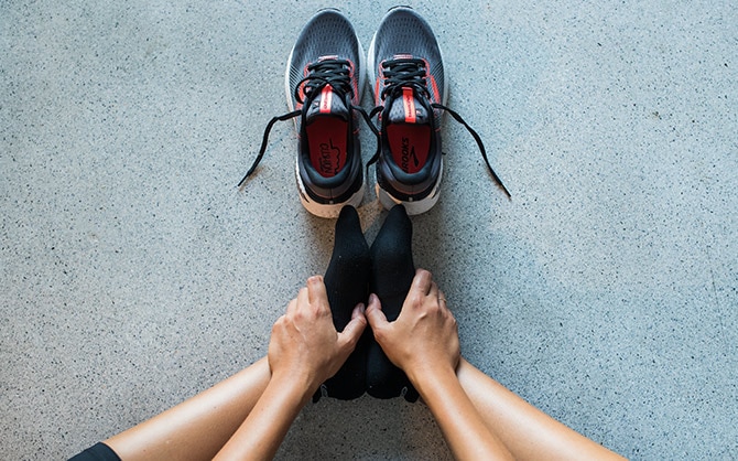 A solo runner shown stretching. The COVID-19 pandemic means giving up group runs for solo workouts.