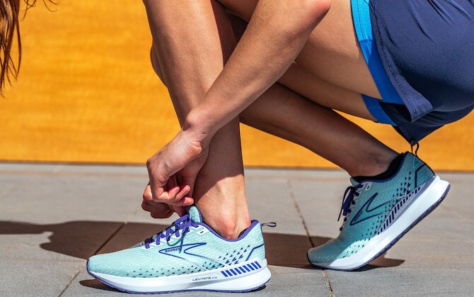 A close-up shot of a runner adjusting their shoes while crouching.