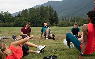 Sportler sitzen im Kreis und dehnen sich