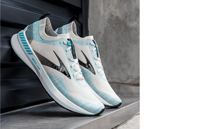 Une paire de chaussures de course sur route Bedlam 3 de Brooks est placée contre un mur.