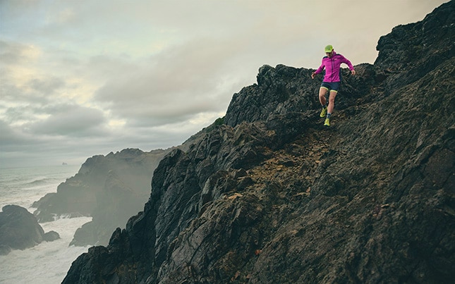 a person running on a rocky along a coastline