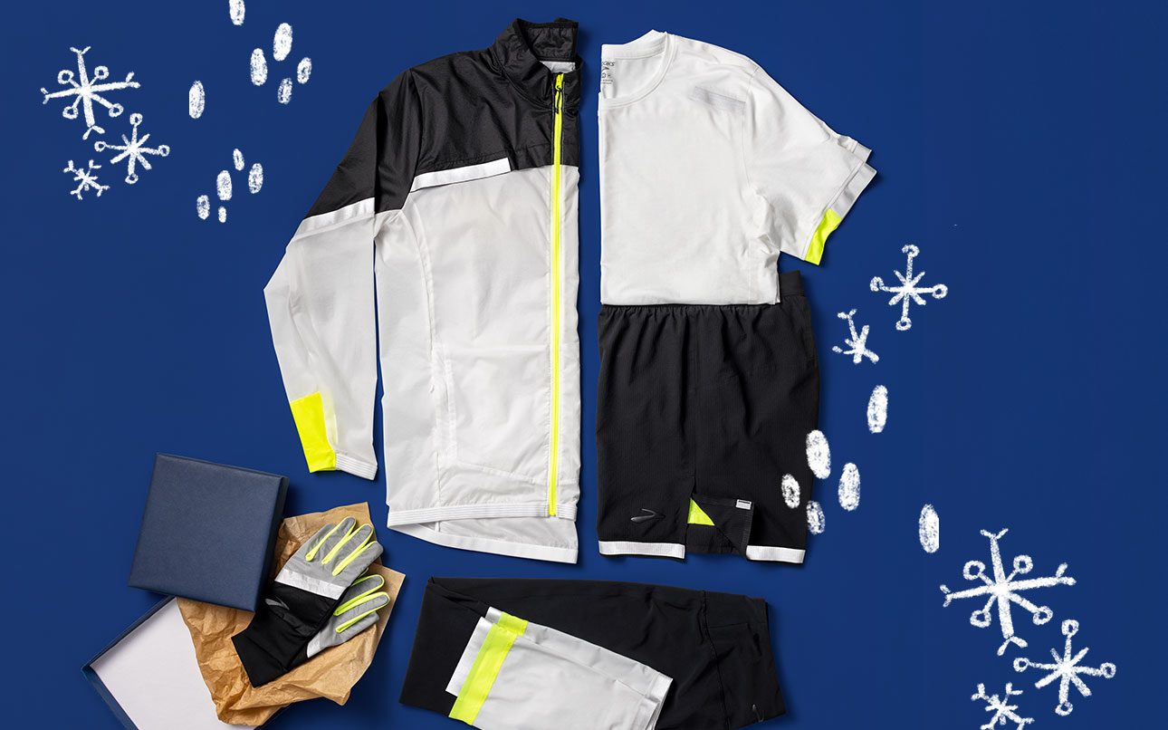 A styled grouping of Run Visible gear, including clockwise from top, Men's Carbonite Jacket (black and white with reflective strips), Men's Carbonite Short-Sleeve (white with reflective strips), Men's Carbonite 7" 2-in-1 Short (black with reflective strips), Unisex Carbonite Glove (black and white with reflective strips), Men's Carbonite Tight (black and white with reflective strips) 