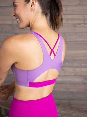 Woman seen from behind wearing Brooks pink running bra and shorts