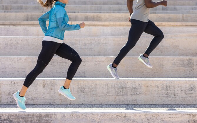 Two runners jog alongside a painted wall