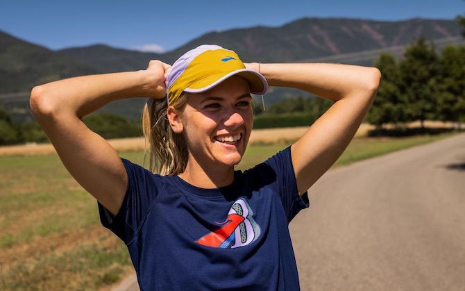 Un runner sorridente che indossa un cappello a protezione della pelle prima di un’uscita.
