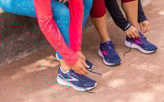 Two runners tying their Brooks shoes before a run