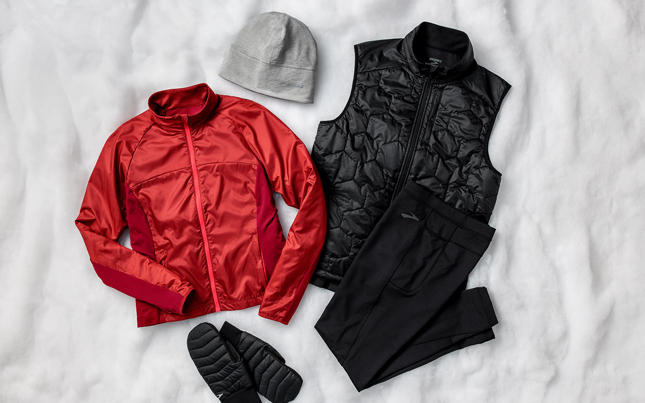 A styled photo of gear, clockwise from top: Notch Thermal Beanie, Shield Hybrid Vest, Momentum Thermal Tight, Cascadia Thermal Mitten, Fusion Hybrid Jacket  