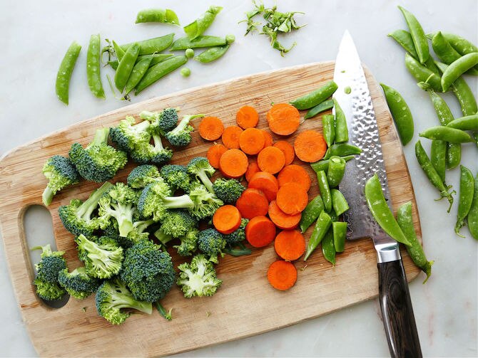 Broccoli, carrots, and peas on a cutting board
