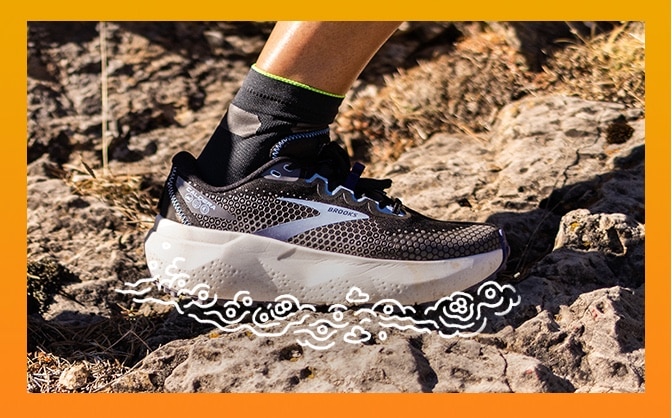 Gros plan d’un pied portant une chaussure de course sur sentier Brooks entouré de bulles.