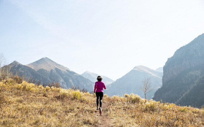 Runner running down a trail with mountains in the background