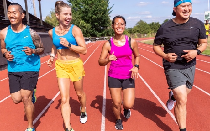 A group of runners on a track running side by side, more close up
