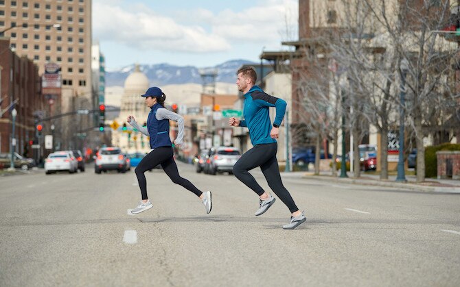 Side view of two runners mid-stride while running on a city street