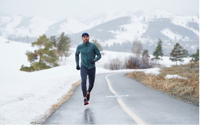 A runner on a snow-lined road during the winter.
