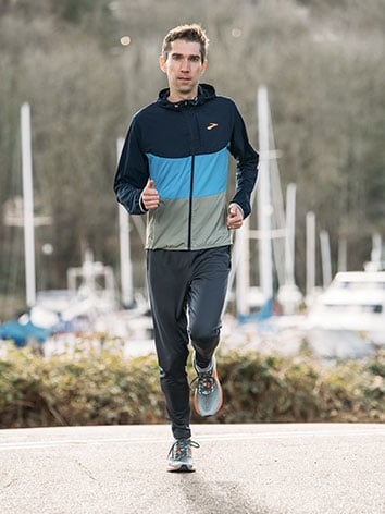 Runner che corre con scarpe e giacca Canopy di Brooks