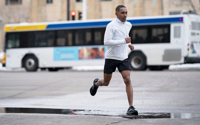 A runner steps in a puddle of water while running in the rain.