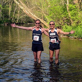 Two runners with an arm around one another.