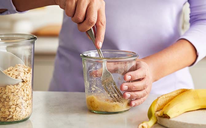 Eine Banane wird in einem kleinen Glas zerdrückt
