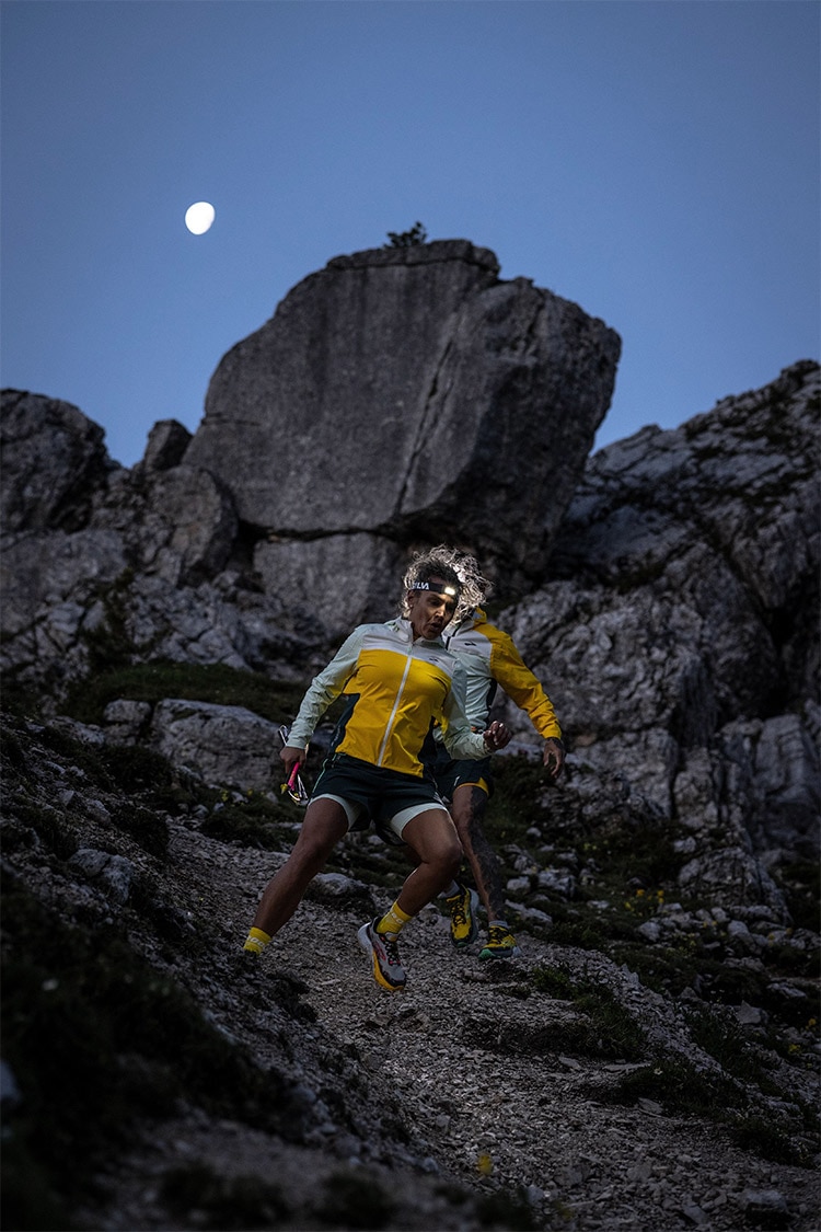 Long shot of a woman and a man running down a hill while wearing Brooks Caldera 7 running shoes