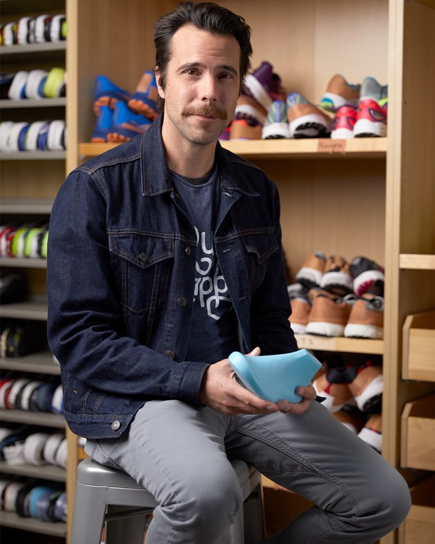 Zach souriant à la caméra avec un modèle de pied dans ses mains