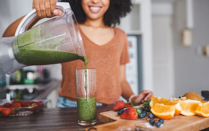 Femme faisant une boisson fouettée verte