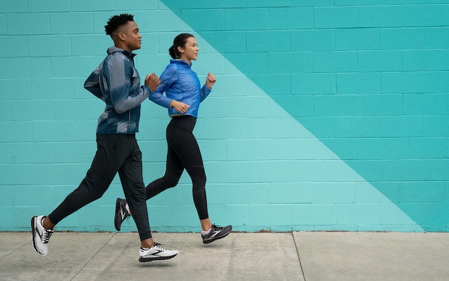 Deux coureurs courent le long d’un mur peint