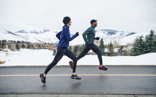 Two runners with a snowy scene in the background