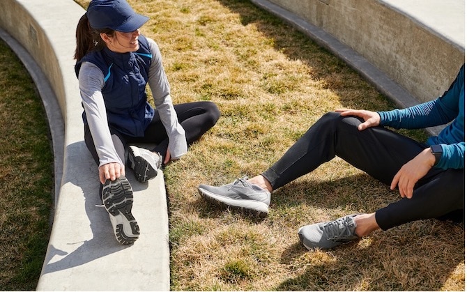 Deux coureurs assis au sol et récupèrent après une course de marathon.